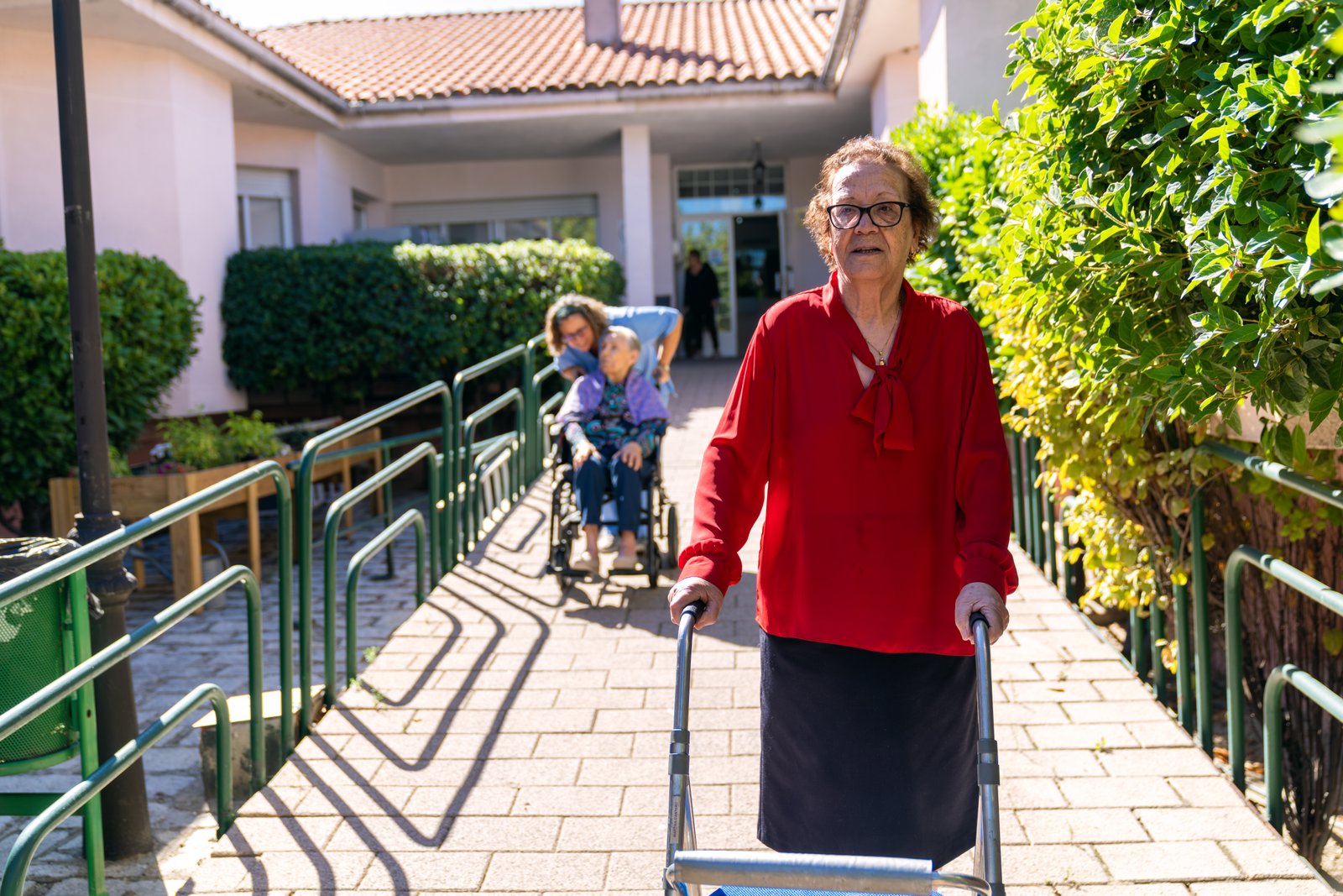 Elderly woman using walker in nursing home garden